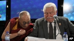 The Dalai Lama, right, looks at the remarks of Lech Walesa, former president of the Republic of Poland, during a news conference after the final session of the World Summit of Nobel Peace Laureates, Chicago, April 25, 2012.