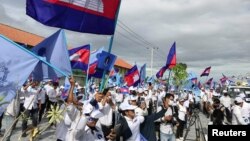 FILE - Supporters of the opposition party, Candlelight Party, wave flags as they take part in a campaign rally for the upcoming local elections on June 5, in Phnom Penh, Cambodia May 21, 2022. Picture taken May 21, 2022. REUTERS/Prak Chan Thul