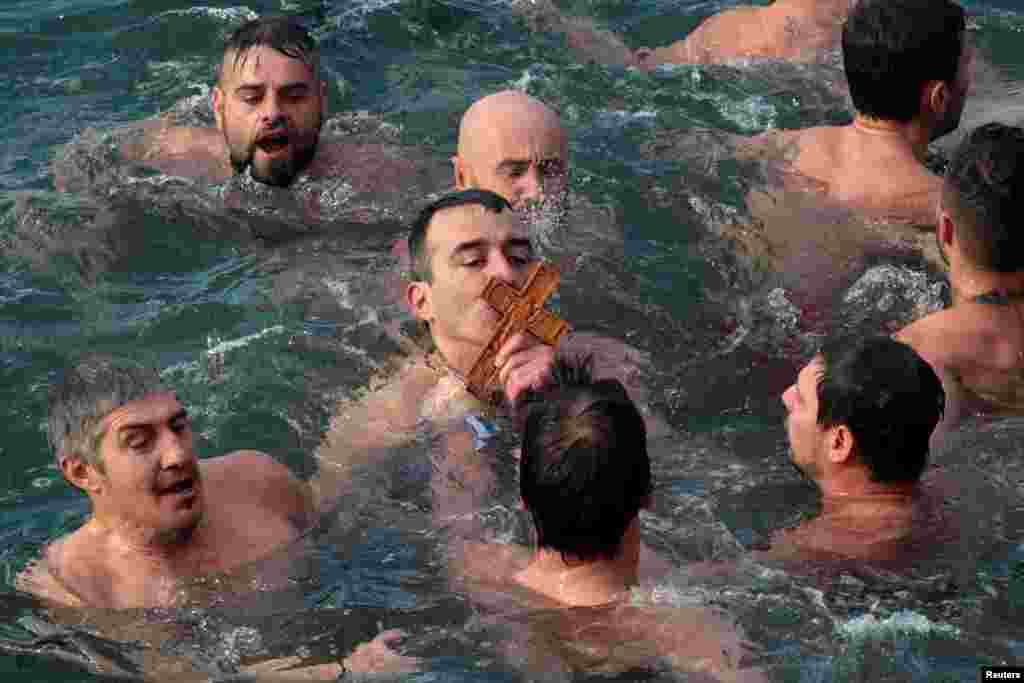 Seorang pria Ortodoks yang setia mencium kayu salib saat berlangsungya perayaan Epiphany di Thessaloniki, Yunani.