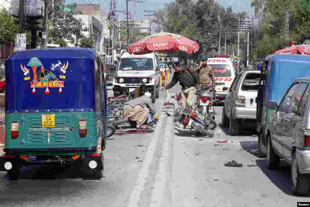 Security officials gather at the site of a bomb blast in Peshawar, Pakistan, March 29, 2013. 