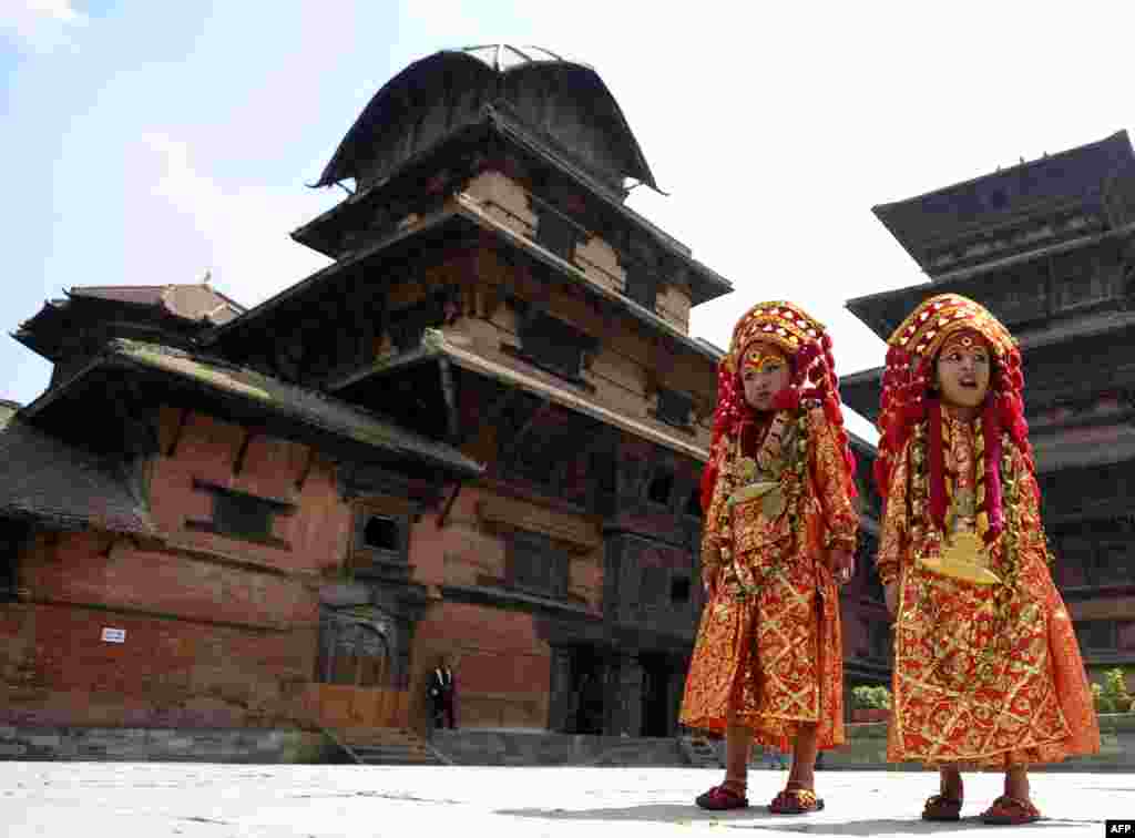 Young Nepalese girls dressed in the outfit of a Kumari, the living goddess, pose during Kumari Puja rituals at Hanuman Dhoka in Durbar Square of Kathmandu.