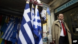 A man walks next to a kiosk selling Greek flags in Athens, February 21, 2012, the same day eurozone finance ministers approved a $172 billion bailout deal to help the debt-laden country avert default.