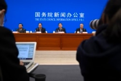 Officials are seen at a press conference at the State Council Information Office in Beijing, China, Dec. 4, 2021. China's Communist Party has taken American democracy to task, sharply criticizing a global democracy summit being hosted by President Biden.