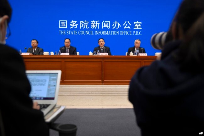 Officials are seen at a press conference at the State Council Information Office in Beijing, China, Dec. 4, 2021. China's Communist Party has taken American democracy to task, sharply criticizing a global democracy summit being hosted by President Biden.