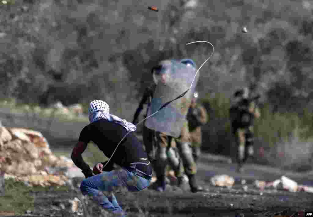 A Palestinian demonstrator uses a device to throw rocks toward Israeli security forces during clashes with them following a weekly demonstration in the occupied West Bank village of Kfar Qaddum.