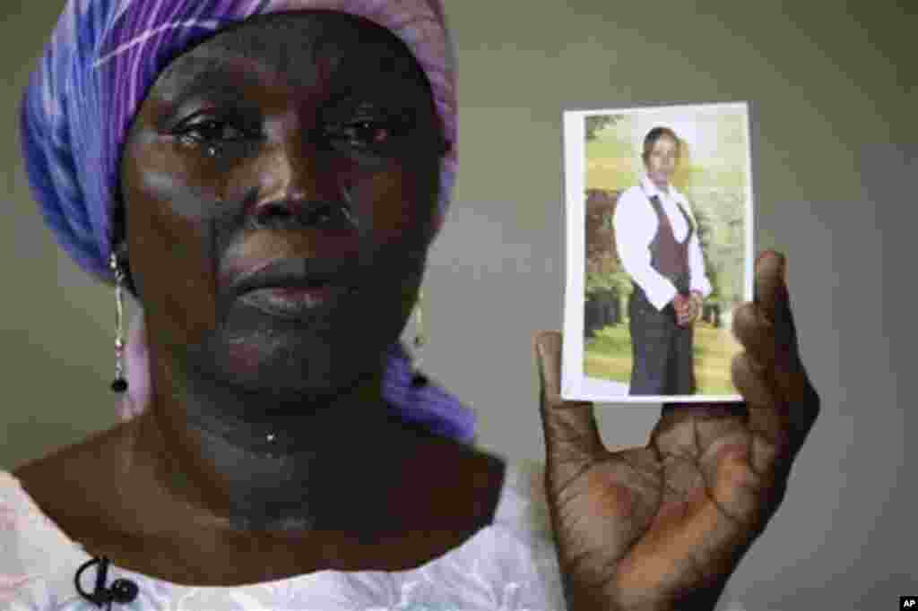 FILE - In this Monday, May 19, 2014 file photo, Martha Mark, the mother of kidnapped school girl Monica Mark cries as she displays her photo, in the family house, in Chibok, Nigeria. At least 11 parents of the more than 200 kidnapped Nigerian schoolgirls