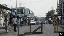 People walk down a road barricaded with tables, in Abidjan, Ivory Coast, 17 Dec 2010