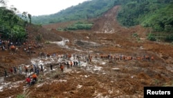 Tentara dan tim SAR berjalan melewati lumpur dalam upaya pencarian korban tanah longsor di desa Sampang, Banjarnegara (13/12).