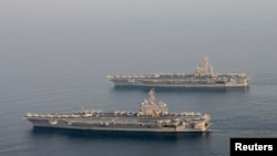 FILE - The U.S. Navy aircraft carrier USS Carl Vinson (CVN 70), bottom, is seen relieving the USS George H.W. Bush in the Arabian Gulf, Oct. 18, 2014. 