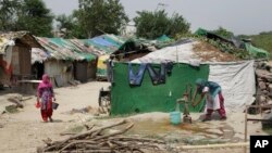 A Rohingya refugee woman draws water from a hand pump at a temporary shelter in New Delhi, India, Aug. 16, 2017.