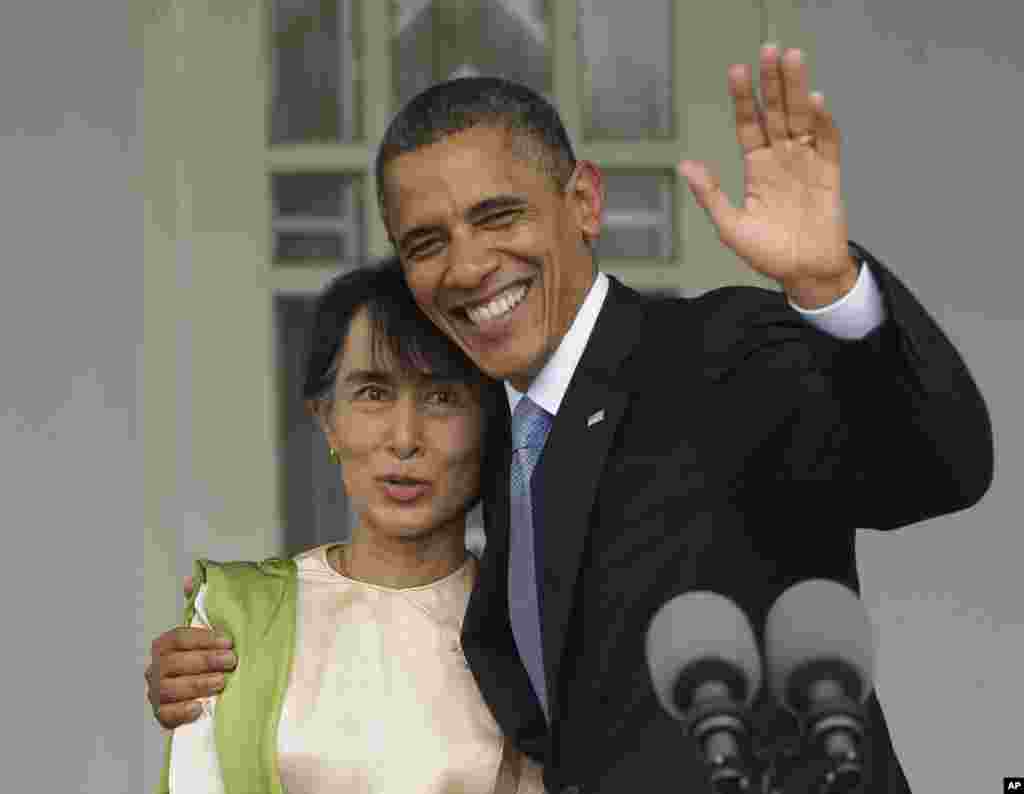 US President Barack Obama, right, waves as he embraces Myanmar democracy activist Aung San Suu Kyi at her residence in Rangoon, Burma, Nov. 19, 2012.