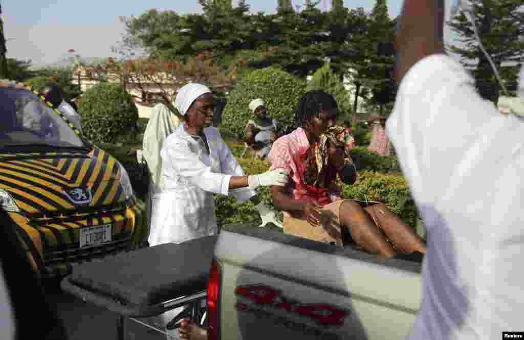 A nurse helps an injured bomb victim sitting at the back of a pickup truck at the Asokoro General Hospital in Abuja, April 14, 2014.