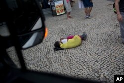 A homeless person sleeps on the sidewalk, seen from the window of a van in Rio de Janeiro, Brazil, Dec. 10, 2017.