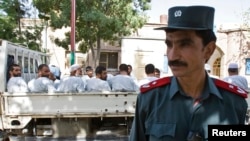 An Afghan police officer stands guard in front of a truck carrying Afghan prisoners on their way to court in Herat, western Afghanistan, August 16, 2009.