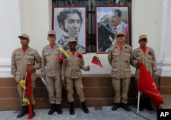 Militia members pose for a photo next to images of Venezuelan independence hero Simon Bolivar, left, and the late President Hugo Chavez, outside Venezuela's National Assembly, in Caracas, Aug. 4, 2017.