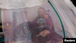 FILE - An Afghan woman and children, who are among displaced families fleeing the violence in their provinces, sit inside a tent at a makeshift shelter at Shahr-e Naw park, in Kabul, Afghanistan, October 4, 2021.