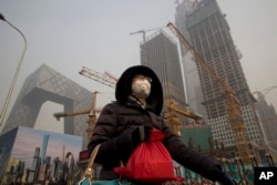 A woman wears a mask as she walks past a construction site as smog continues to choke Beijing, China, January 6, 2017.