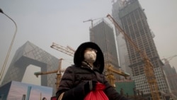 A woman wears a mask as she walks past a construction site as smog continues to choke Beijing, China, Jan. 6, 2017.
