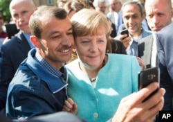 FILE - German Chancellor Angela Merkel poses for a selfie with a refugee in a facility for arriving refugees in Berlin, Sept. 9, 2015.
