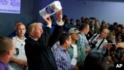 El presidente Donald Trump lanza toallas de papel a una multitud mientras reparte víveres en San Juan, Puerto Rico.