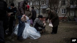 FILE - Local residents receive humanitarian aid in Vostochniy district of Mariupol, Ukraine.