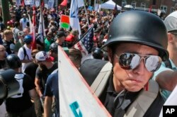 FILE - A white nationalist demonstrator with a helmet and shield walks into Lee Park in Charlottesville, Va., Aug. 12, 2017.
