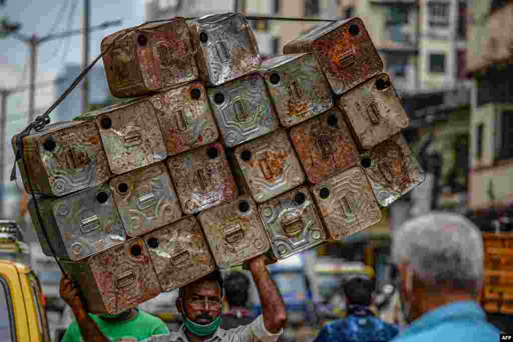 A laborer carries a load of empty oil tins in Dharavi in Mumbai, India.