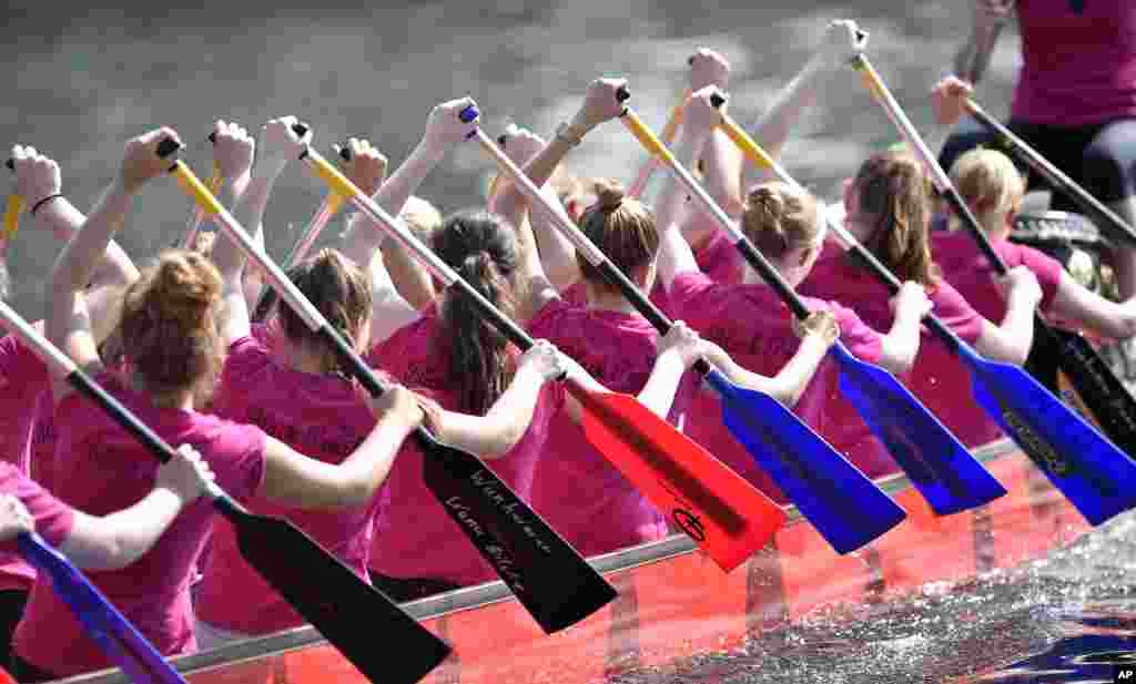 Participants paddle in a dragon boat during a regatta at the old industrial harbor in Duisburg, Germany.