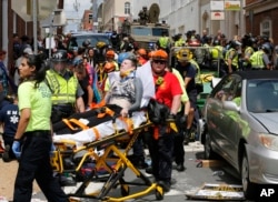 FILE - In this Aug. 12, 2017, photo, rescue personnel help injured people who were hit when a car ran into a large group of protesters after a white nationalist rally in Charlottesville, Va.