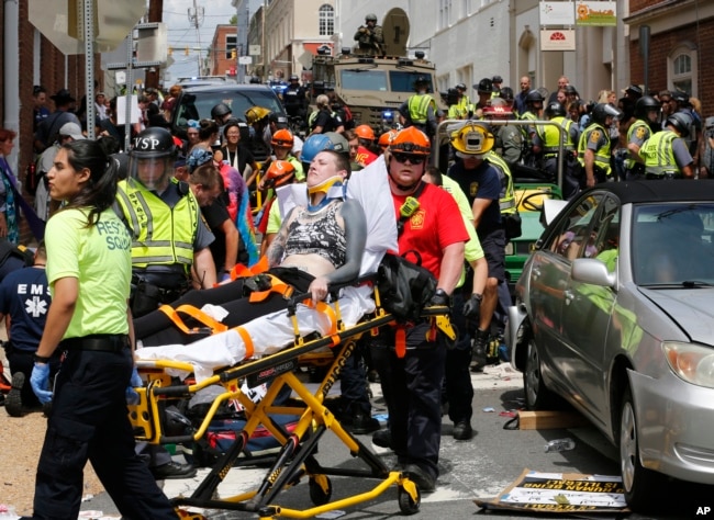 FILE - In this Aug. 12, 2017, photo, rescue personnel help injured people who were hit when a car ran into a large group of protesters after a white nationalist rally in Charlottesville, Va.