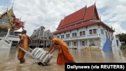 Biksu Buddha menarik gerobak yang membawa karung pasir untuk melindungi sebuah kuil dari banjir di Provinsi Ayutthaya, Thailand, 27 September 2021. (Foto: Dailynews via REUTERS)