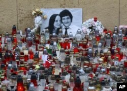 FILE - Candles are seen in front of a photo of journalist Jan Kuciak and his fiancee Martina Kusnirova, in Bratislava, Slovakia, March 9, 2018.