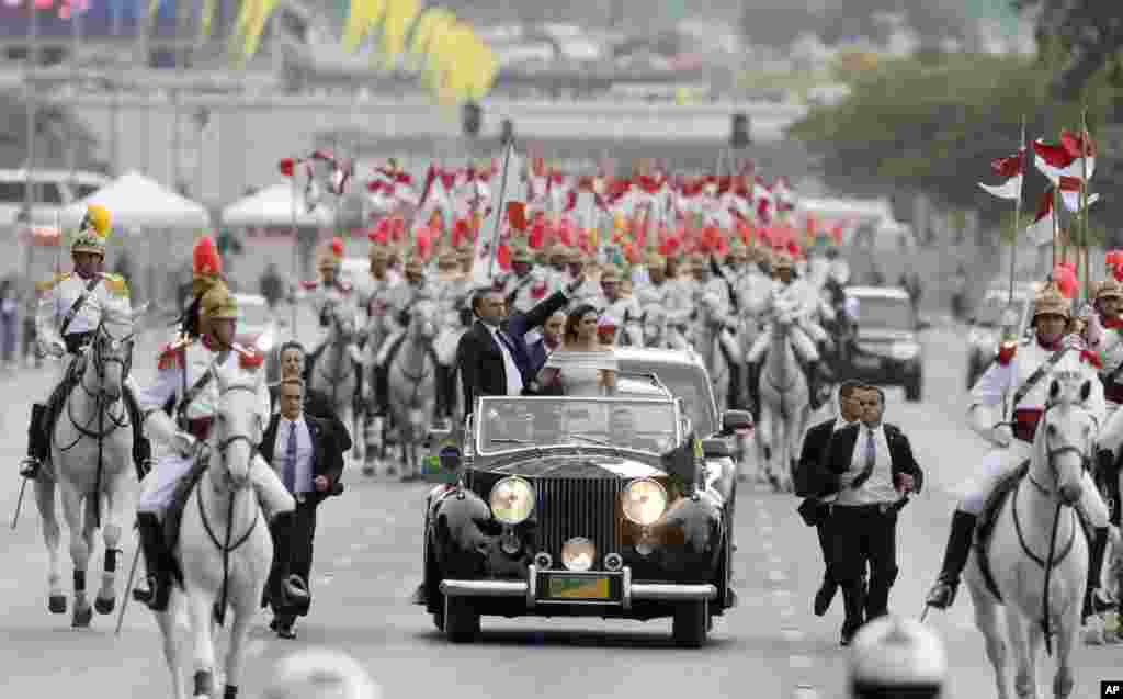 Presiden Brazil Jair Bolsonaro dan ibu negara Michelle Bolsonaro naik mobil terbuka setelah upacara pelantikan di Brasilia pada tahun baru, Selasa (1/1).