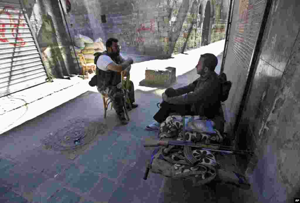 在敘利亞阿勒頗古城露天市場，自由敘利亞軍戰士坐在他們的陣地上，旁邊是關門的店鋪。（2012年9月24日）