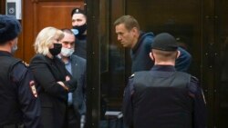 In this handout photo provided by Moscow City Court Russian opposition leader Alexei Navalny talks to his lawyers standing in the cage during a hearing to a motion from the Russian prison service to convert the suspended sentence of Navalny from the 2014