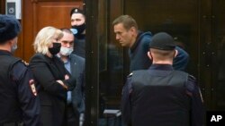 In this handout photo provided by Moscow City Court Russian opposition leader Alexei Navalny talks to his lawyers standing in the cage during a hearing to a motion from the Russian prison service to convert the suspended sentence of Navalny from the 2014