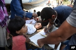 A man writes the names of the migrants who will cross to Macedonia in small groups as they wait in the northern Greek town of Idomeni, Sept. 3, 2015.