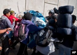 Cientos de migrantes, incluyendo mujeres y niños, convocaron una protesta pacífica en el lado mexicano de la frontera cuando las autoridades mexicanas les ordenaron parar a la espera de un permiso para la manifestación.