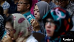 A woman, who had family on the crashed Lion Air flight JT610, prays at a news conference about the recovery process at a hotel in Jakarta, Nov. 5, 2018. 