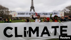 Environmentalists hold a banner that reads "Standing and Determined for the Climate" at a climate conference protest demonstration near the Eiffel Tower in Paris, France, Dec. 12, 2015.