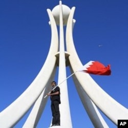 Demonstrator waves Bahraini flag on the Pearl Monument on a main square in Manama, Bahrain, February 15, 2011