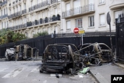 Burned cars sit in a street of Paris, Dec. 2, 2018, a day after clashes during a protest of yellow vests (gilets jaunes) against rising oil prices and living costs.