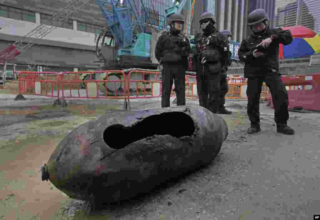 Police officers from explosive ordinance disposal stand next to a deactivated bomb in the Wan Chai district of Hong Kong. Hong Kong police neutralized the large unexploded wartime bomb after it was unearthed during construction work in the Asian financial center.