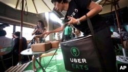 Japan Uber: A delivery man brings ordered food during a press conference of UberEats in Tokyo, Wednesday, Sept. 28, 2016.