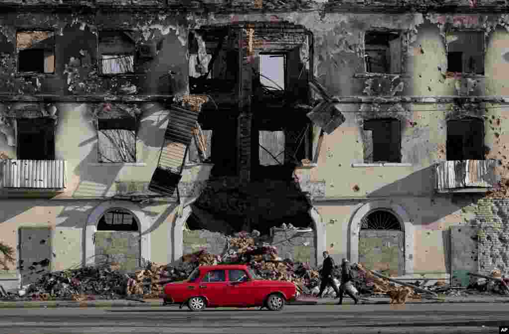 People pass by a destroyed building in Vuhlehirsk, Ukraine.