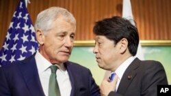 U.S. Defense Secretary Chuck Hagel, left, talks with Japanese Defense Minister Itsunori Onodera, right, as they wait for South Korean Defense Minister Kim Kwan-jin to arrive to begin their meeting, Saturday, May 31, 2014 in Singapore.