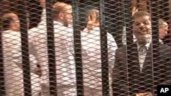 FILE - A Nov. 2013 image made from video provided by Egypt's Interior Ministry shows ousted President Mohammed Morsi (R), speaking from the defendant's cage during a trial hearing in Cairo, Egypt.