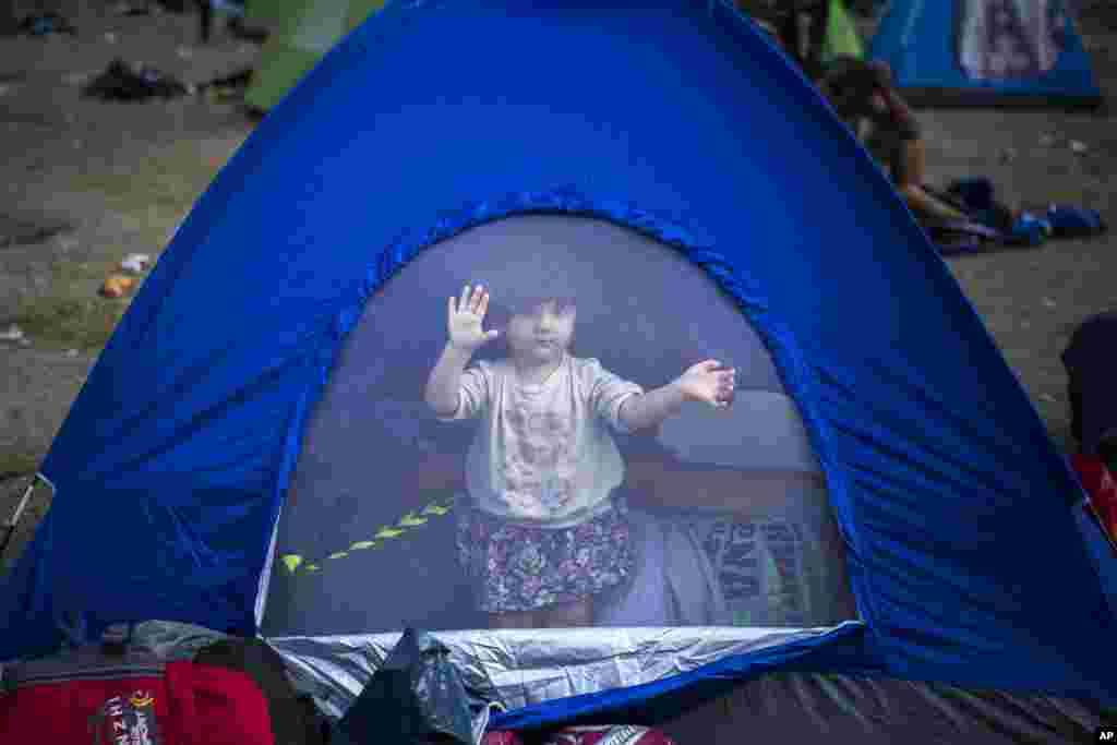 A young refugee wakes up inside a tent at a park in Belgrade, Serbia.