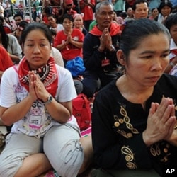 Thai 'Red Shirt' anti-government protesters pray during a ceremony to mark the 60th Coronation Day for King Bhumibol Adulyadej, inside their fortified camp in the financial central district of Silom in downtown Bangkok, 05 May 2010