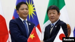 Vietnam's Industry and Trade Minister Tran Tuan Anh, left, and Japan's Minister of Economic Revitalization Toshimitsu Motegi shake hands after a news conference on the Trans Pacific Partnership (TPP) Ministerial Meeting during APEC 2017 in Danang, Vietnam